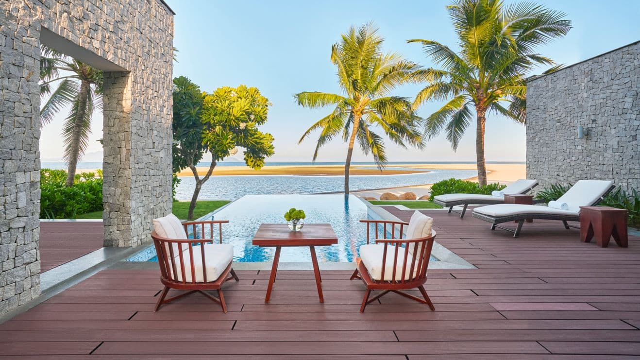 Villa pool deck with loungers overlooking the beach